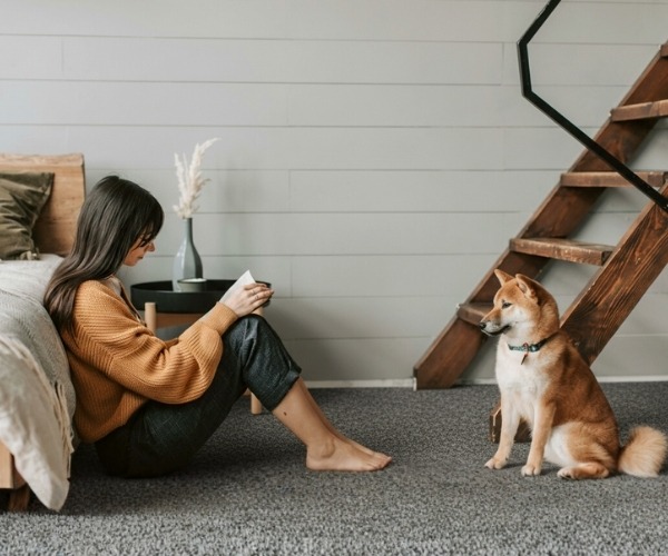 Woman sitting on soft grey carpet flooring in Melbourne bedroom.